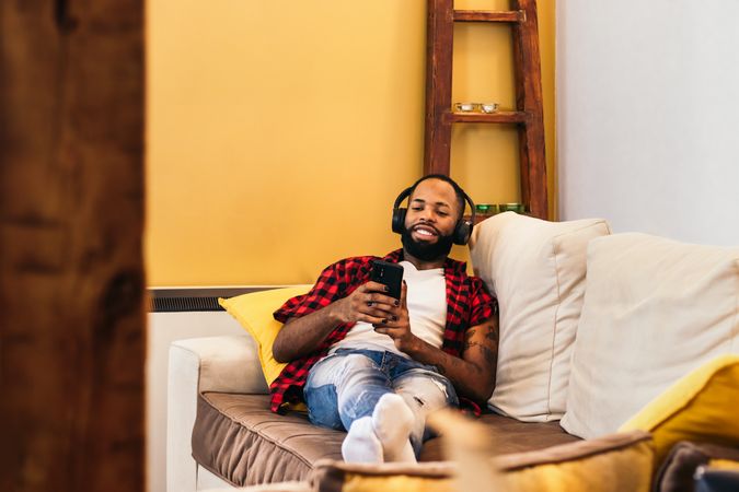 Black man relaxing using smartphone on the sofa at home