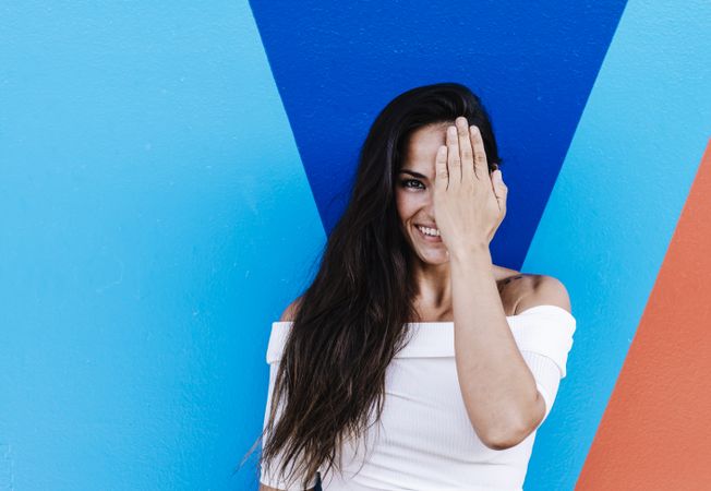 Elegant young woman leaning against a wall while hiding the face with hand