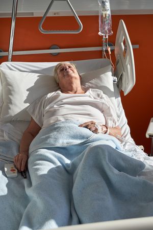 Ill woman sleeping on medical bed in hospital