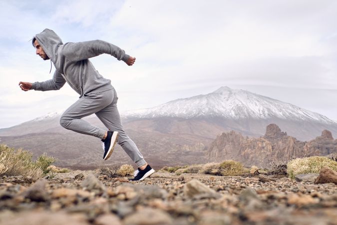 Active concentrated man running on stony ground