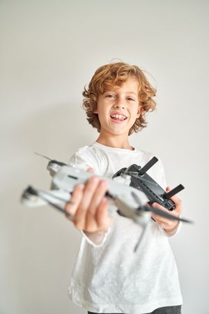 Cheerful preteen boy showing drone copter with remote control