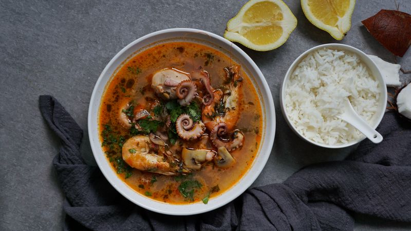Soup of octopus and shrimps near rice and lemon