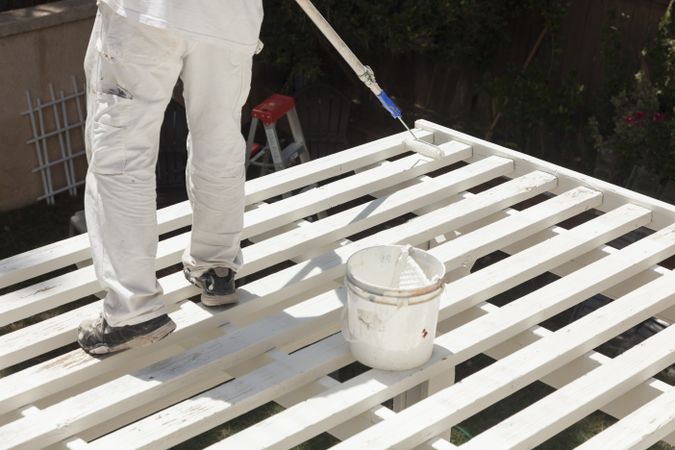 Painter Rolling Paint Onto Top of Patio Cover