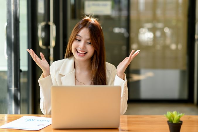 Young woman in suit chatting online with laptop happily.