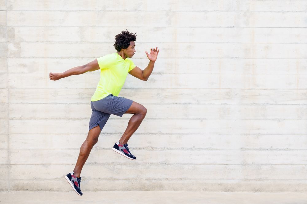 Side view of man sprinting in neon shirt