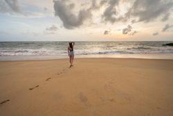 Woman in beachwear walking on sand barefoot