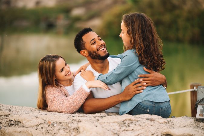Cheerful multiethnic family cuddling on nature