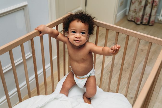 Cute toddler in diaper in crib