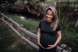 Happy pregnant woman standing at river in park