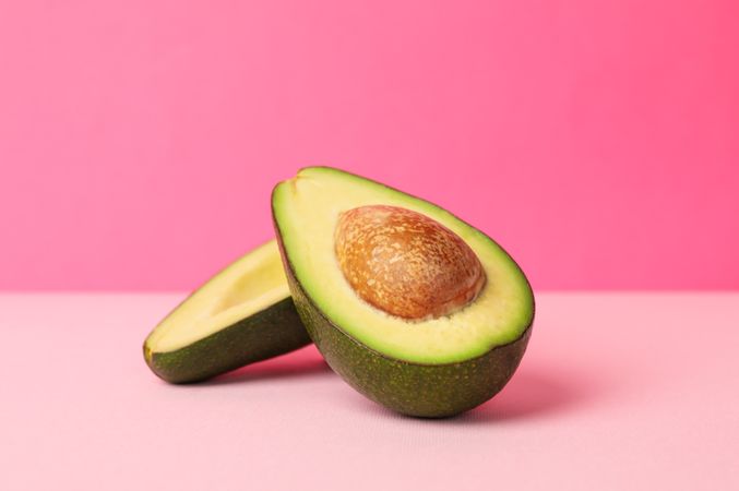 Ripe fresh avocado on pink background, space for text
