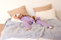 Girl napping in bed with teddy bear in purple pajamas.