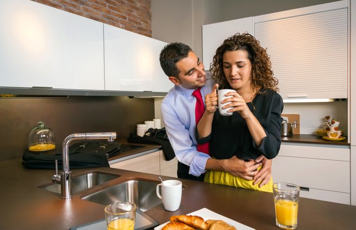 Happy businessman embracing woman while having fast breakfast before work