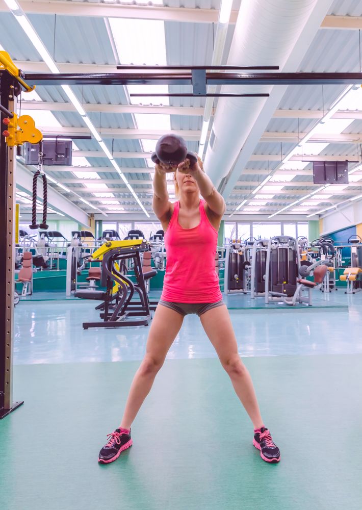Woman in pink shirt doing kettle bell swings