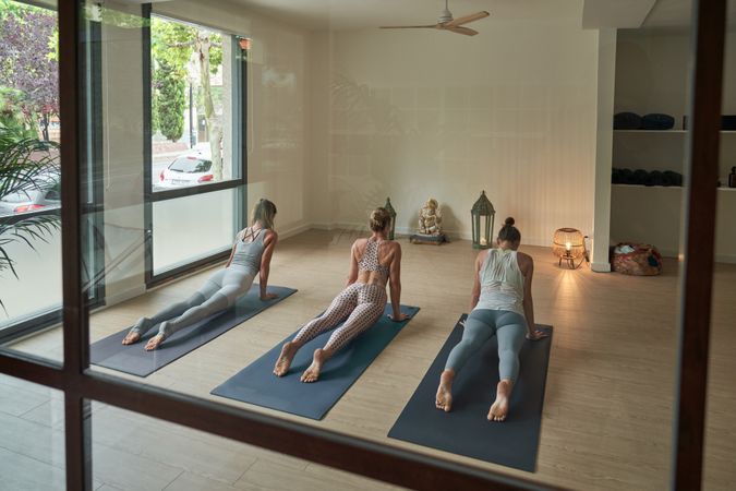 Group of unrecognizable women doing yoga in Bhujangasana in studio