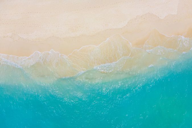 Aerial shot of waves coming up on a clear tropical beach