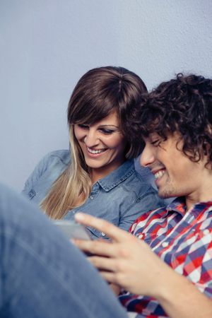 Cute couple in love looking smartphones and laughing