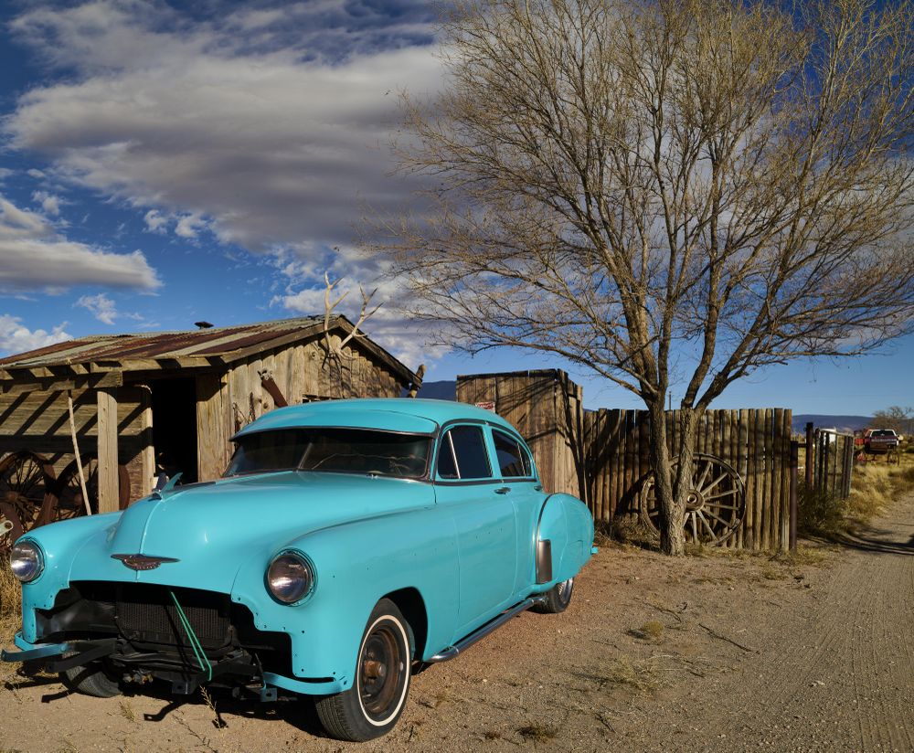 Vintage bright car parked among a wooden lodge and fence