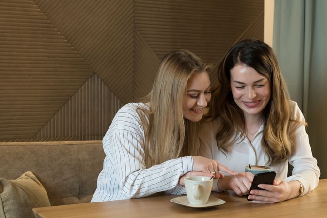 Young women looking at phone in cafe