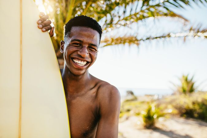 Cheerful man standing with surfboard