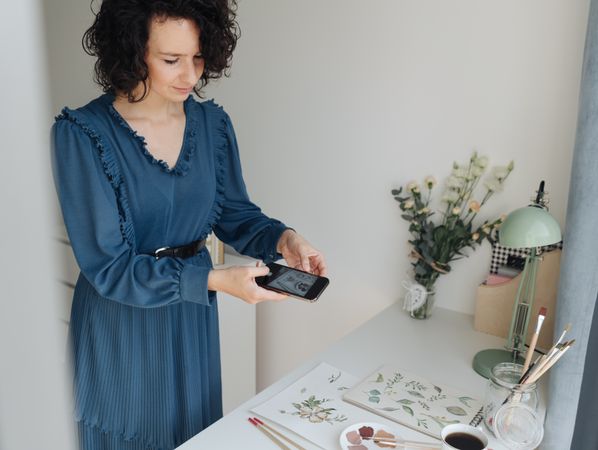 Artist photographing drawings with smartphone