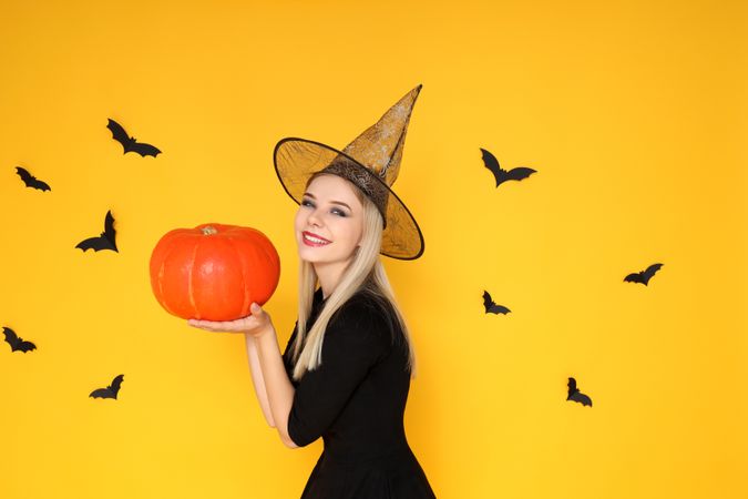 Concept of Halloween, young woman on yellow background
