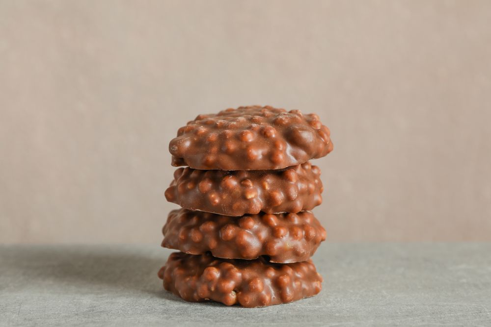 Stack of chocolate cookies on grey table against light background, space for text