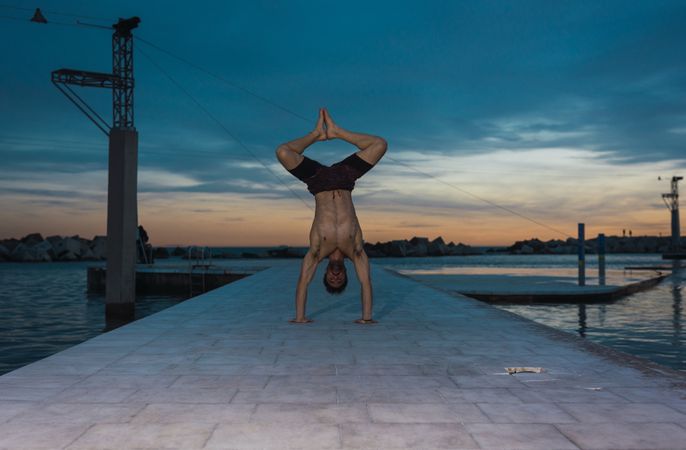 Athletic man balancing on hands on embankment
