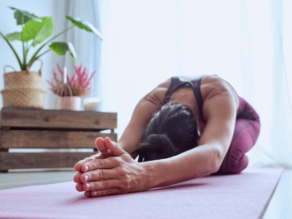 Faceless woman practicing Utthita Balasana posture