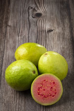 Fresh sliced guavas on wooden table.