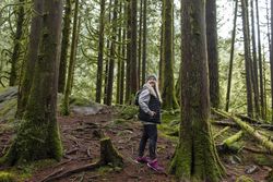 Older woman looking over her shoulder while exploring the woods