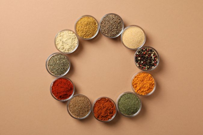Circle of bowls of spices on beige table