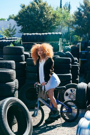 Full length photo of young Black woman standing over small bike at tire shop