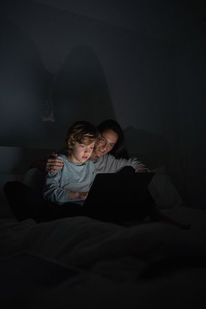 Woman helping son to do homework on laptop