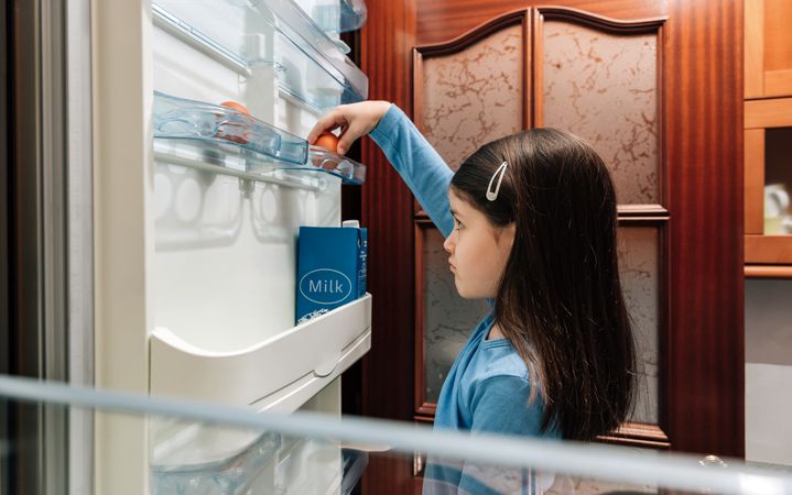 Sad girl taking an egg from the empty fridge