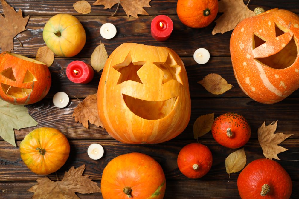Pumpkins, leaves and candies on wooden background, top view