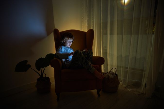 Boy playing on tablet in dark room