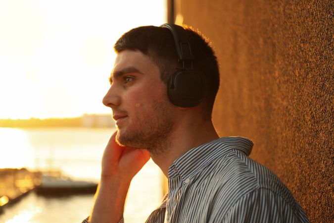 Young man in headphones listen music. Amazing sunset