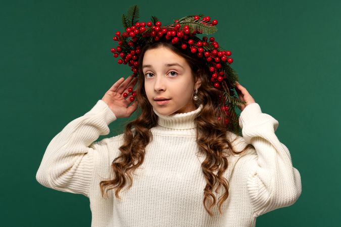 Girl wearing wreath of red berries and green fir branches.
