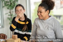 Two female students laughing over fallen building blocks 0JLz84