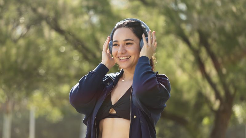 A young woman wearing invisible orthodontic aligners, smiles happily, listening to music with her headphones