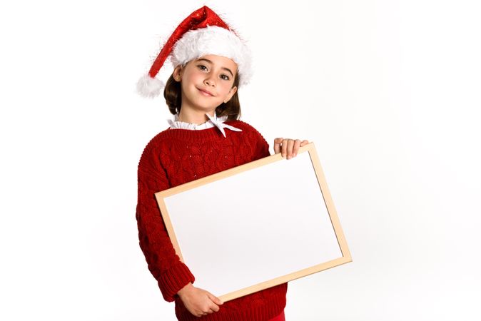 Child in Santa costume holding blank board