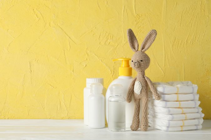 Baby hygiene accessories on wooden table against yellow background