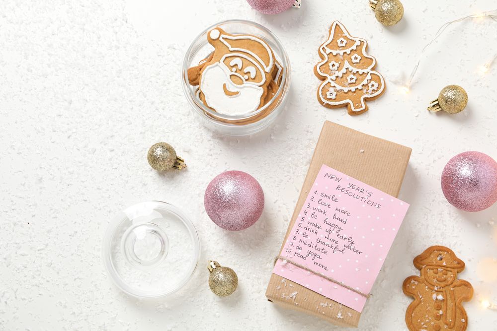 Cookies and paper with list on box on plain background, top view