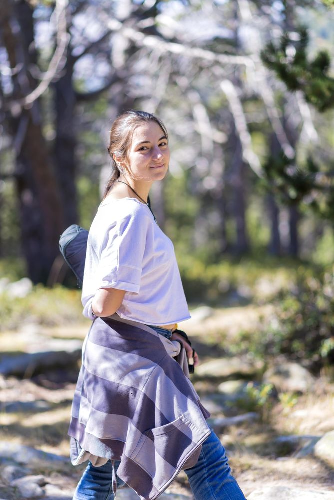 Young woman standing in forest, vertical composition