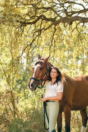 Charming horsewoman embracing horse in forest
