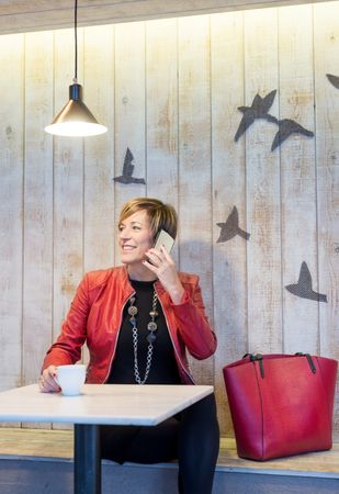 Professional woman dressed in red speaking on phone in restaurant