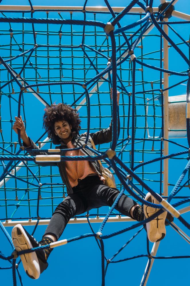 Woman with afro hair climbing by children's attractions.