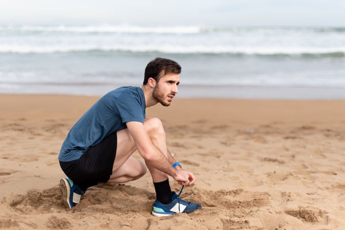 Sportsman tying shoelaces on beach