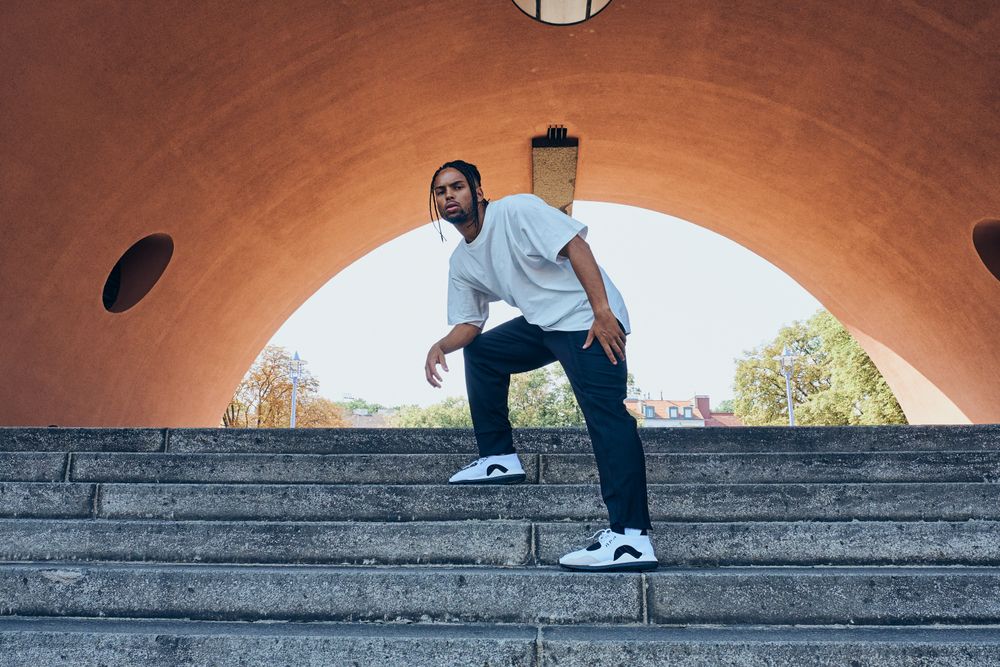 Trendy Black man posing near modern arch
