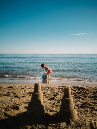 Sandy little towers and girl on seaside